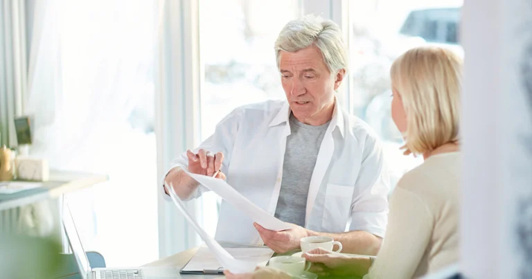 A man and woman sit at a table reviewing papers related to key clauses in veterinary employment contracts